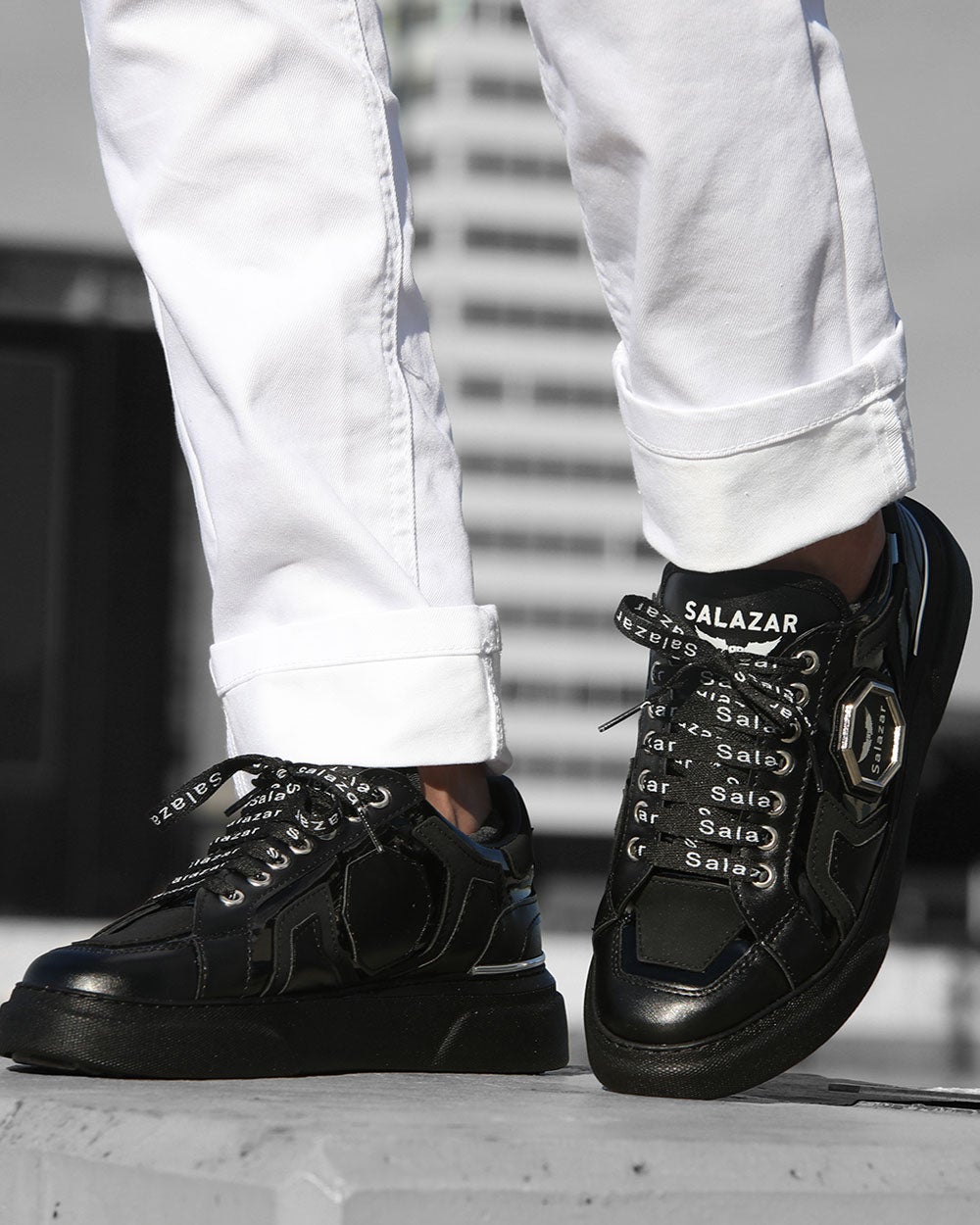 Trendy black sneakers with laces with white writing and metal badge and black sole for men