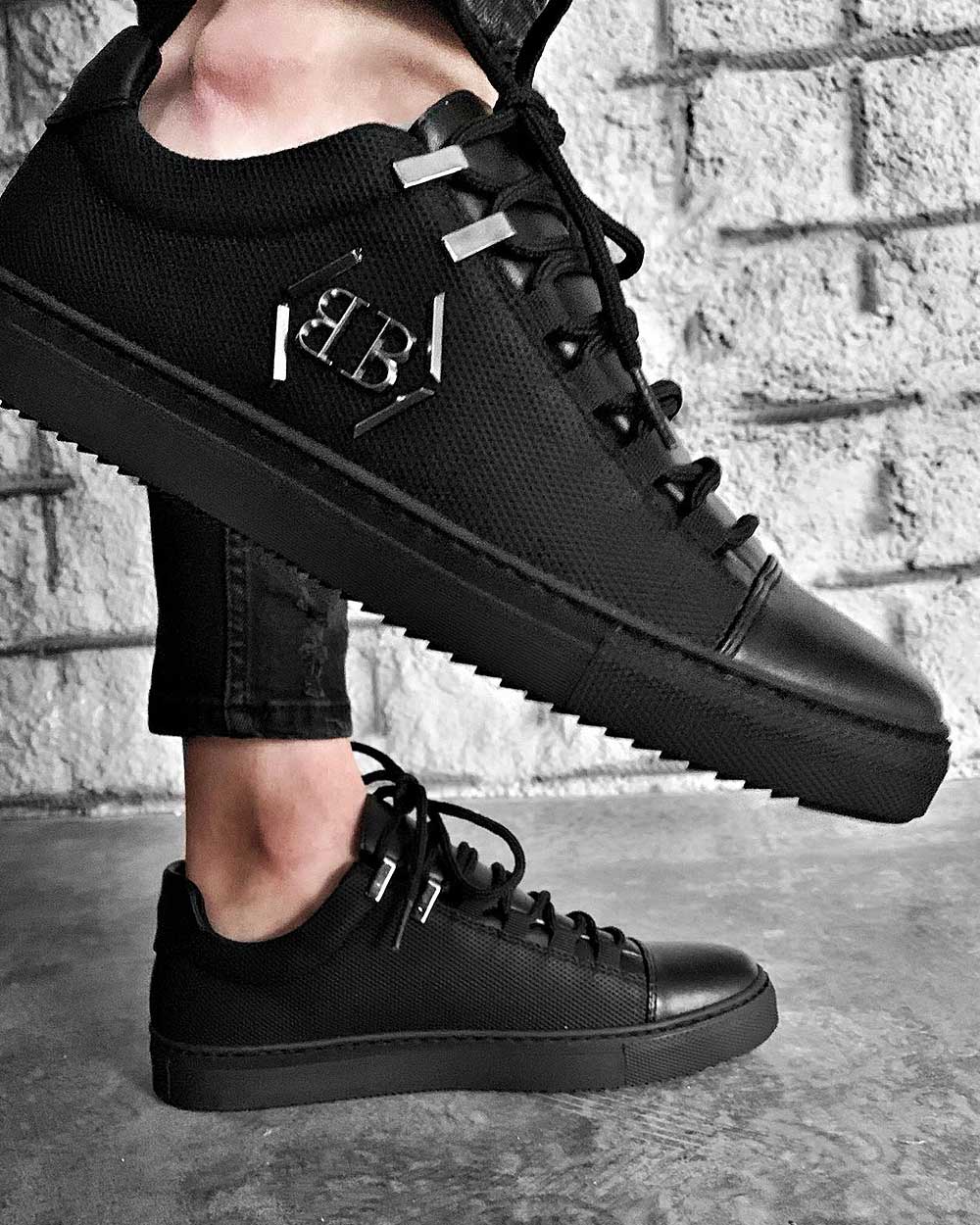 Trendy black sneakers with metal logo and black notched soles for men