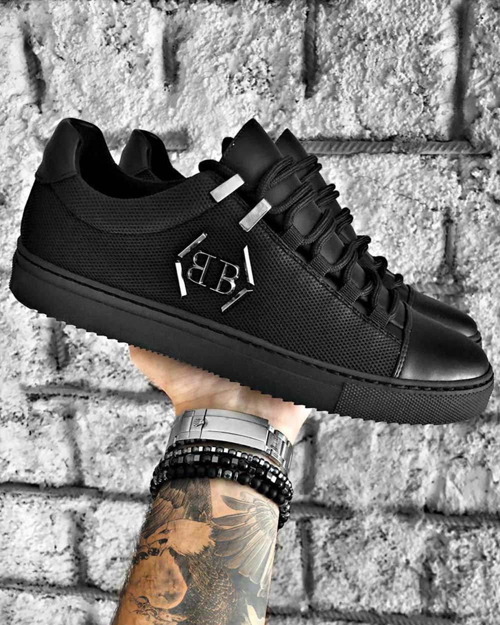 Trendy black sneakers with metal logo and black notched soles for men