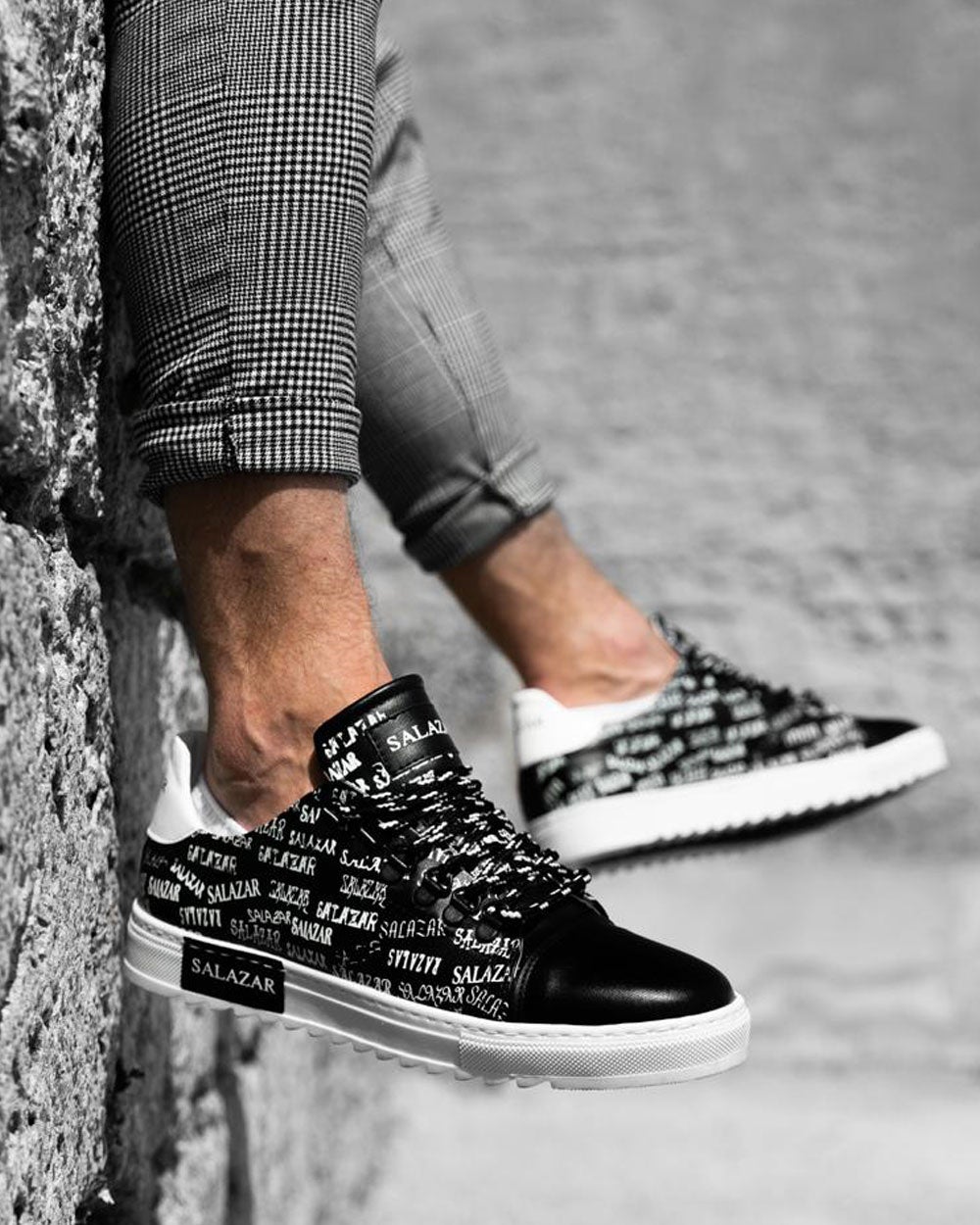 Trendy black sneaker shoes with monogram writing and white notched soles for men