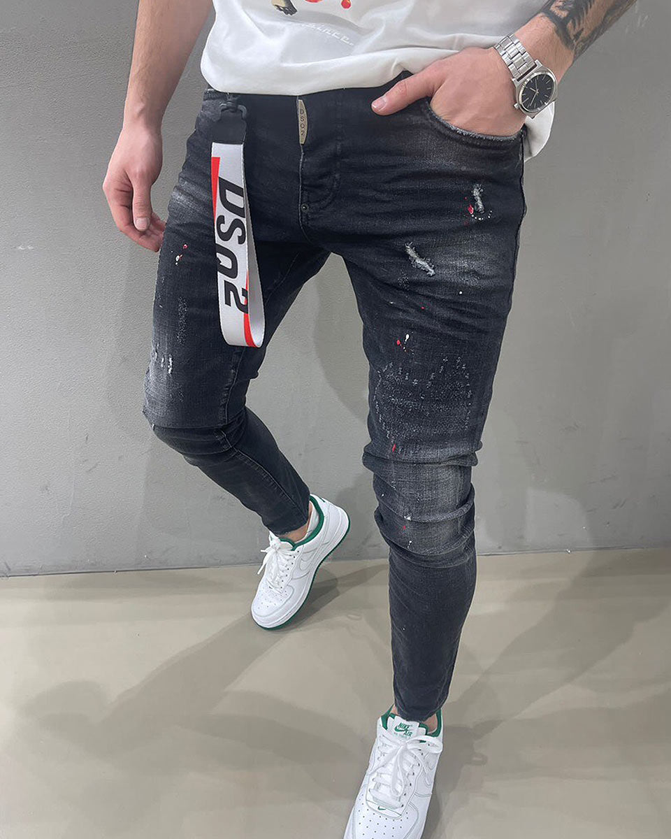 Distressed faded black slim jeans with destroyed paint stains effect icon for men